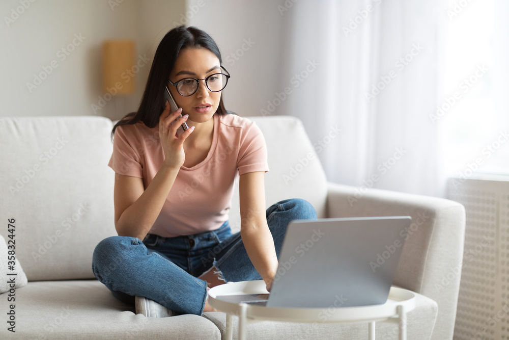 Girl Working On Laptop Talking On Mobile Phone Sitting Indoors Girl Working On Laptop Talking On Mobile Phone Sitting Indoors
