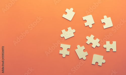Conceptual image of chaotically lying puzzles with a place under the text on an orange background. Order, Puzzle, Jigsaw Piece, Connection, Leisure Games. The view from the top
