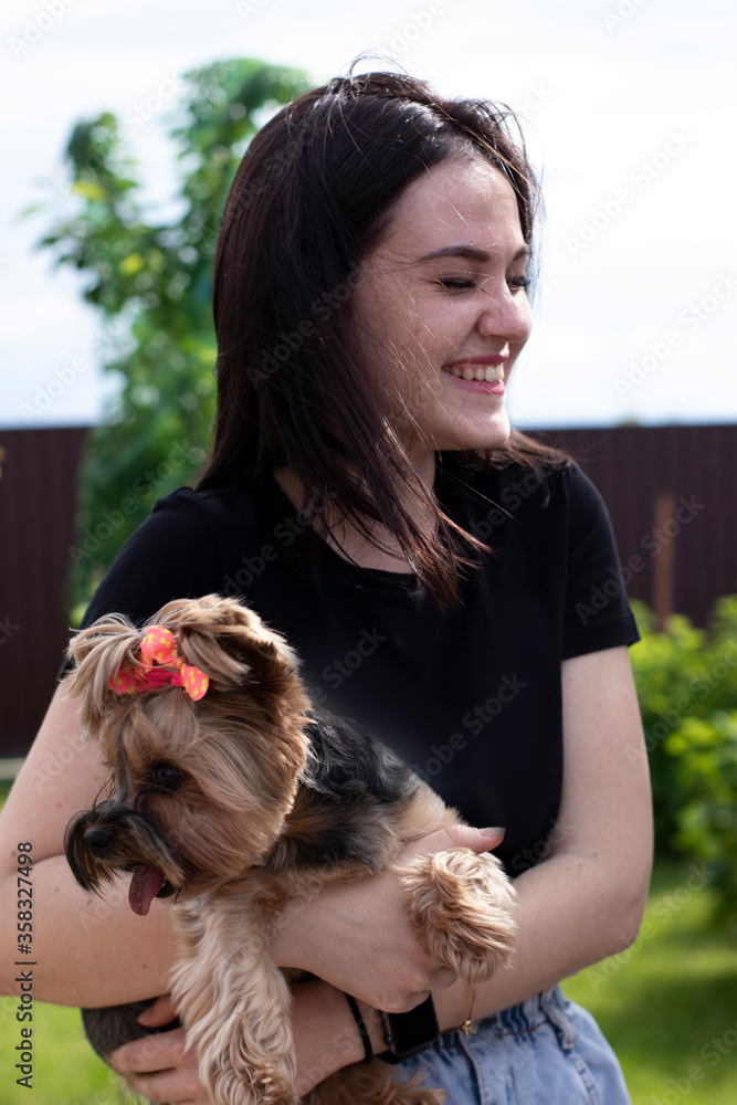 charming young brunette woman in a black T-shirt and denim shorts with a cute dog Yorkshire terrier in her arms. High quality photo charming young brunette woman in a black T-shirt and denim shorts with a cute dog Yorkshire terrier in her arms. High quality photo