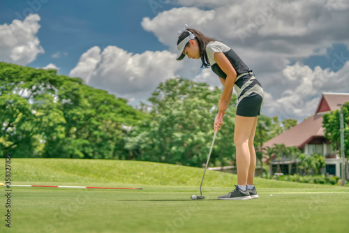 woman playing golf with putter club on course.