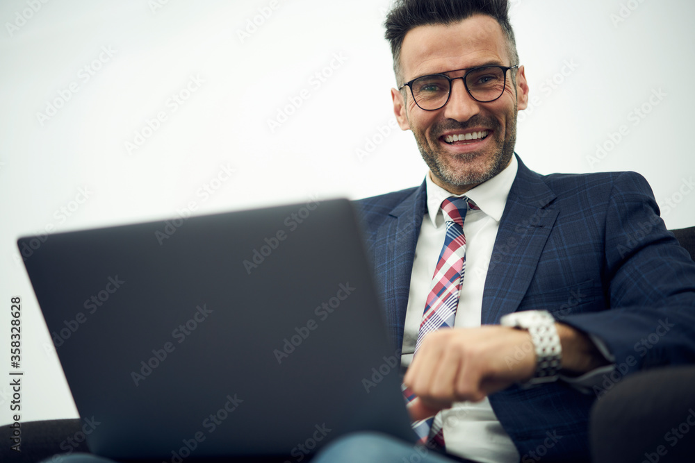 Cheerful handsome mature entrepreneur in glasses feeling excited setting up successful online startup project increasing incomes of corporation checking rates on website using modern laptop computer Cheerful handsome mature entrepreneur in glasses feeling excited setting up successful online startup project increasing incomes of corporation checking rates on website using modern laptop computer