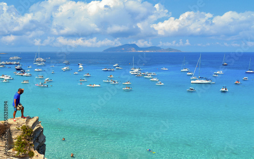 paradise clear torquoise blue water with boats and cloudy blue sky in background in Favignana island  Cala Rossa Beach  Sicily South Italy.