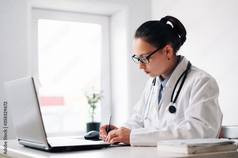 female doctor at her workplace with laptop and clipboard female doctor at her workplace with laptop and clipboard