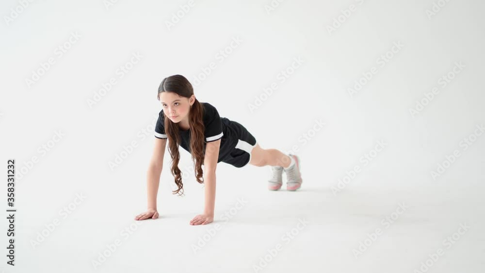Sporty beautiful teenage girl in sportswear doing plank exercise against grey gradient background in studio Sporty beautiful teenage girl in sportswear doing plank exercise against grey gradient background in studio