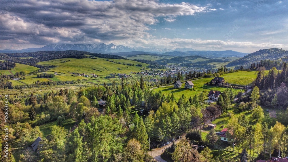 Tatra mountains visible behind a forest and a small village in Poland, Europe