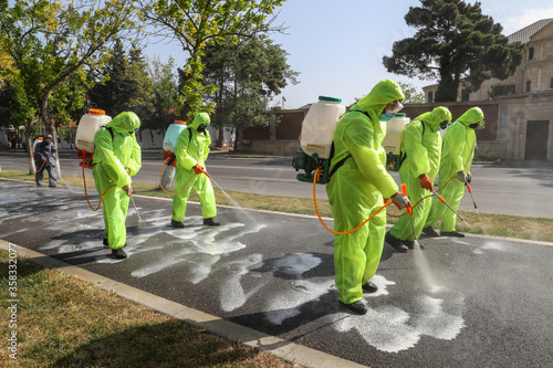 People in protective suits disinfect on the streets of the city. Epidemic corona virus, pandemic worldwide. Disinfection of surfaces from viruses in quarantine. Spraying with disinfectants. Baku 2020 photo