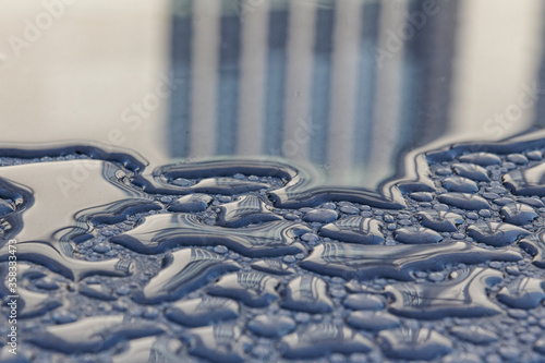 A building facade is reflected in early morning dew drops.