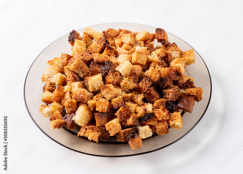 Small pieces of bread fried in oil lying on a transparent brown plate on a light background. Fried crackers. Small pieces of bread fried in oil lying on a transparent brown plate on a light background. Fried crackers.
