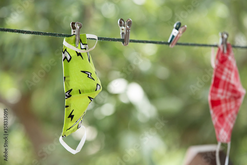 The selective focus of washed fabric facemask are dried and attached with the rope by the clothspin. both of them are dried and kept with spacing like a symbol of social distrancing.  photo