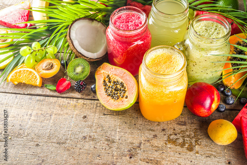 Assorted different fruit smoothies and juices with tropical fresh fruits and berries. Clean eating, healthy lifestyle, diet and vitamin drink beverages concept. Top view flatlay