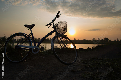 Silhouette Bicycle parking with sunset or sunrise background. It was parking nearby the pond for relaxing