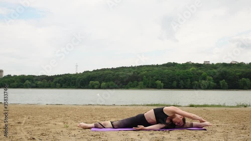 Young woman relaxing on the beach and doing yoga exercises 