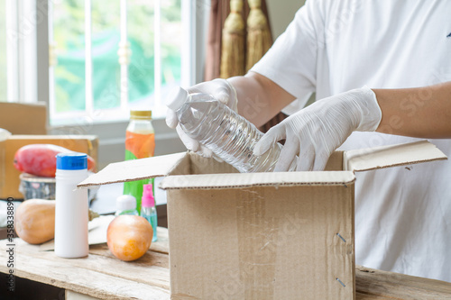 Hand of volunteer wear sanitary gloves packing food or product for delivery service people who get impact by coronavirus, Covid-19. Social distancing concept. photo