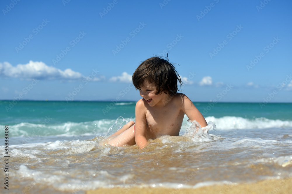Little boy enjoying on beach. Child sit on beach and play in sea on summer vacation Little boy enjoying on beach. Child sit on beach and play in sea on summer vacation