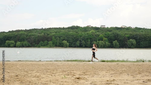 Young girl running near the lake in city park
