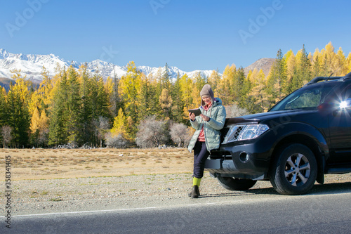 Traveler woman using tablet on mountains road trip. Auto travel concept. © Sergey