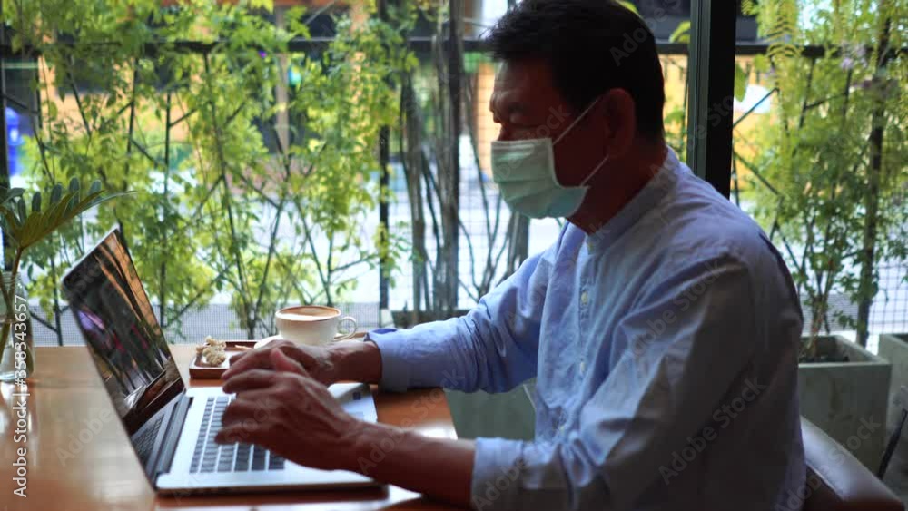 Old man using laptop computer in cafe and wearing mask for prevent the spread of the Covid-19, Covid-19 virus protection concept in Thailand. Old man using laptop computer in cafe and wearing mask for prevent the spread of the Covid-19, Covid-19 virus protection concept in Thailand.
