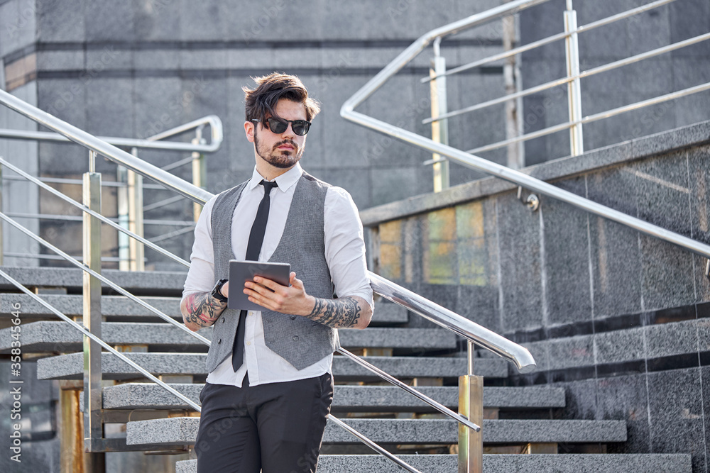 Young Businessman using a tablet pc outside wearing a classic suit Young Businessman using a tablet pc outside wearing a classic suit