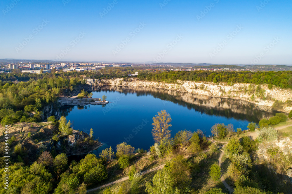 Krakow, Poland. Zakrzowek lake with steep cliffs in place of former flooded limestone quarry in Twardowski Rocks. Popular recreational place. Aerial view at sunrise Krakow, Poland. Zakrzowek lake with steep cliffs in place of former flooded limestone quarry in Twardowski Rocks. Popular recreational place. Aerial view at sunrise