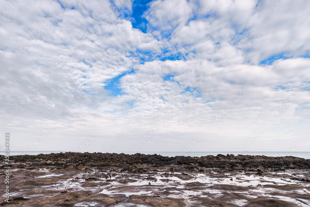 lava Beach with white clouds on jeju island.