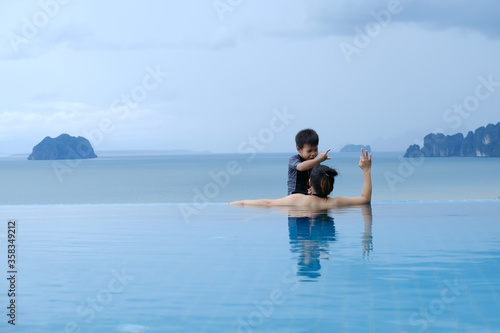 Mother playing with her little cute son in the pool on the sea background. © Jera