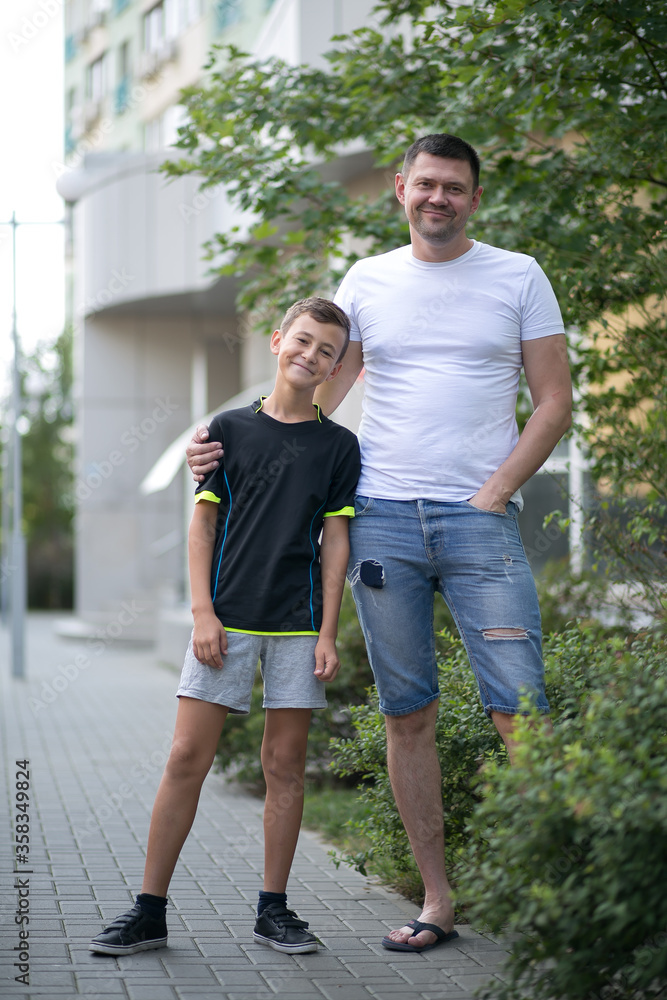 Obraz premium Father and son walking outdoors in summer on the street