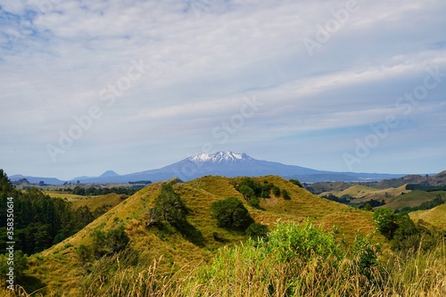 Mt. Tangariro - small Mt. Ngauruhoe in far - green landscape in front. © JaDeLissen