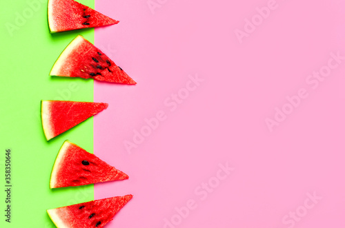 Creative summer food concept. Watermelon pattern. Juicy slices of ripe red watermelon on multicolored pink and green background. Flat lay, top view, copy space. Summer berry, healthy