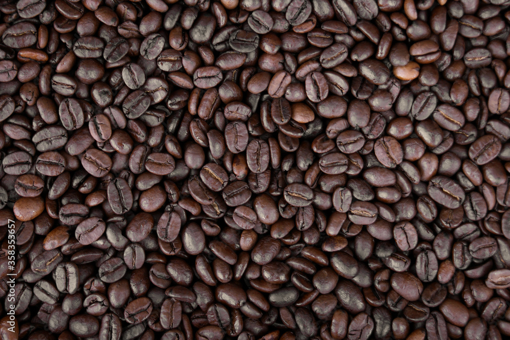 Mixture of different kinds of fresh roasted brown coffee beans in dark tones Mixture of different kinds of fresh roasted brown coffee beans in dark tones