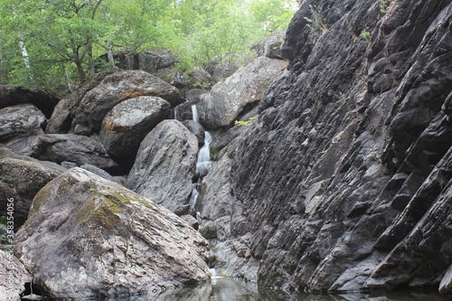 Mountain waterfall. Mountain river among gray huge boulders in the middle of a dense forest