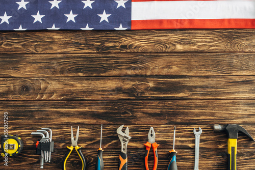 top view of metallic tools and american flag on wooden surface, labor day concept photo