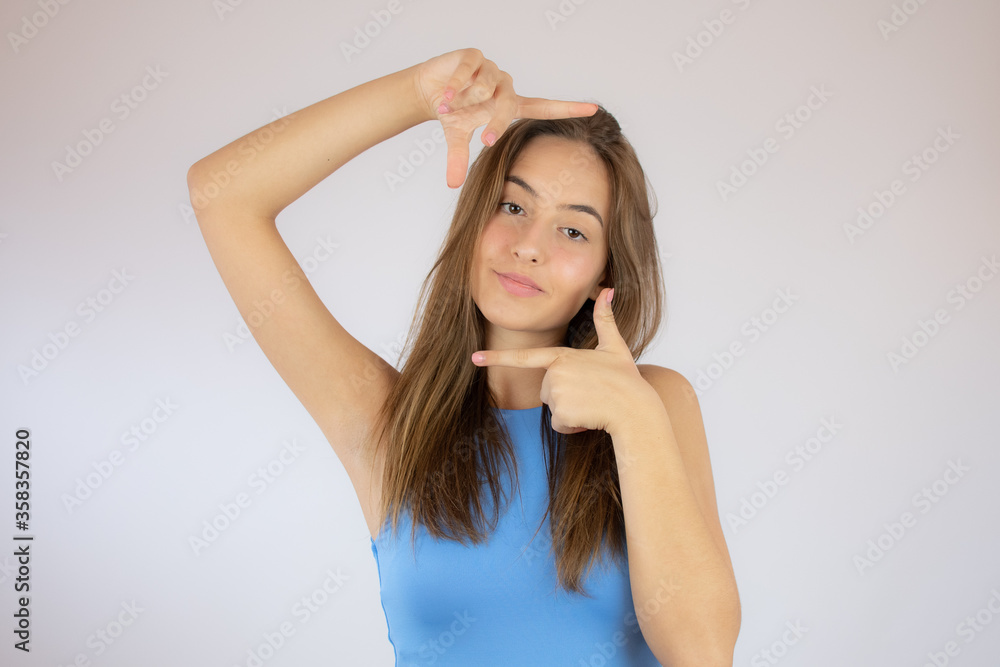Beautiful young girl in blue shirt making portrait gesture