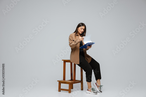 Fashionable  stylish. Young woman in casual wear on gray background. Bodypositive character  feminism  loving herself  beauty concept. Plus size businesswoman during paperwork. Inclusion  diversity.
