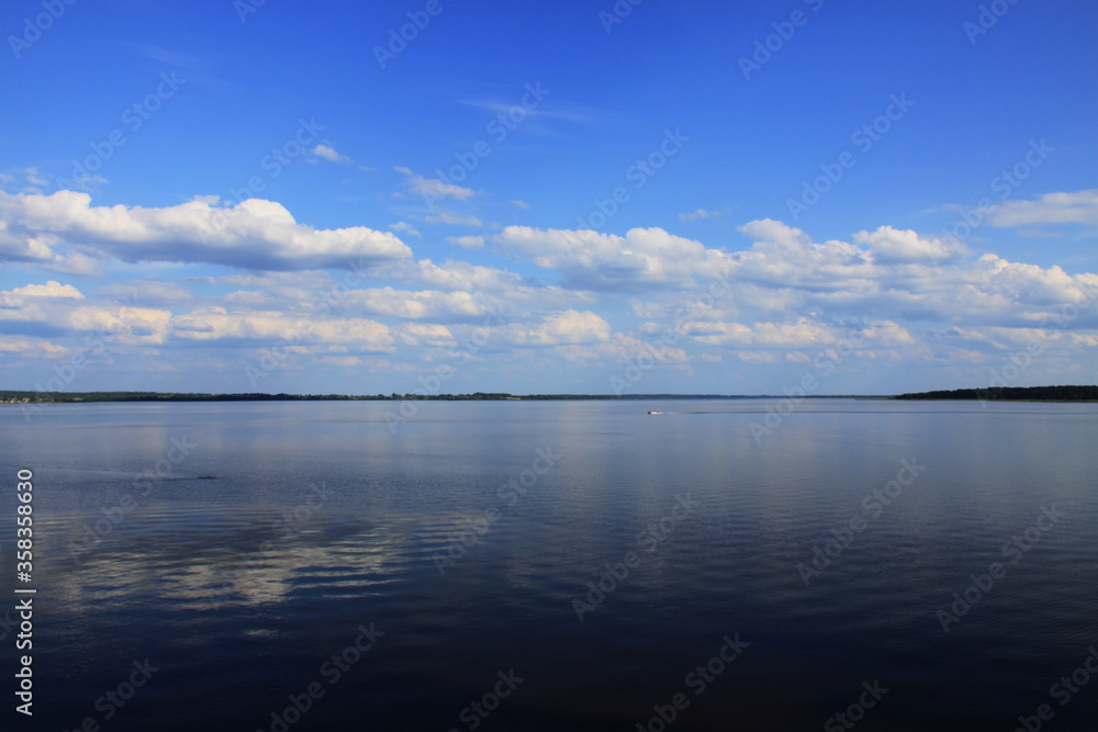 Fototapeta premium Landscape with a lake and white clouds on a blue sky