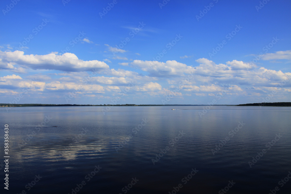 Landscape with a lake and white clouds on a blue sky