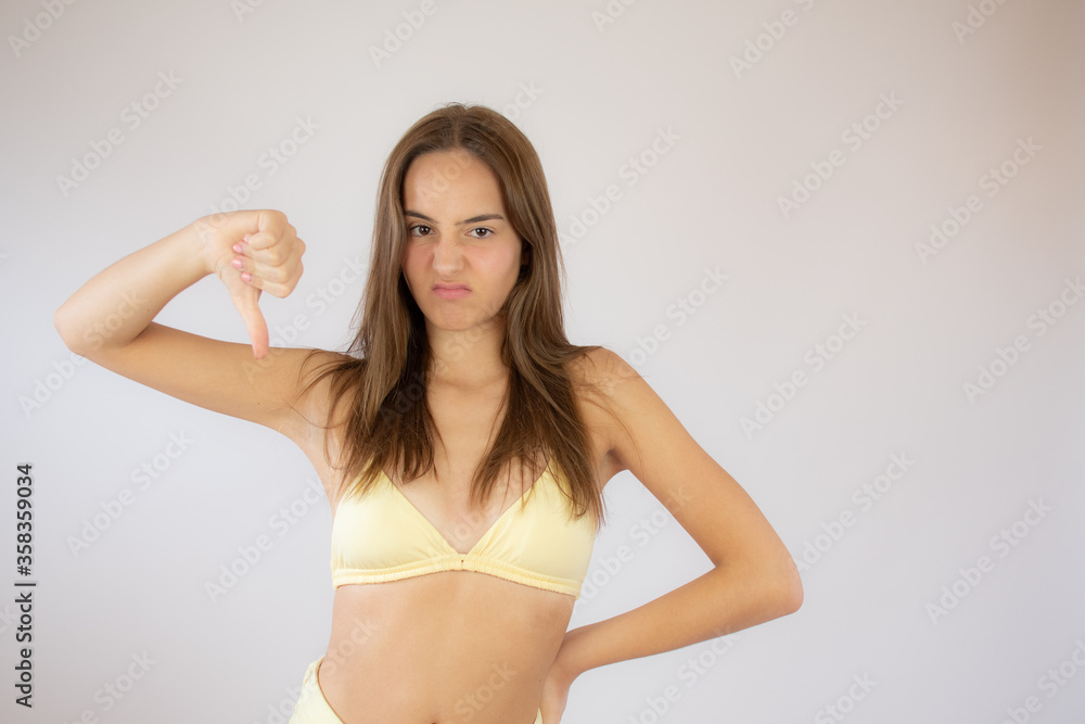 Pretty young girl in bikini making finger down gesture Pretty young girl in bikini making finger down gesture