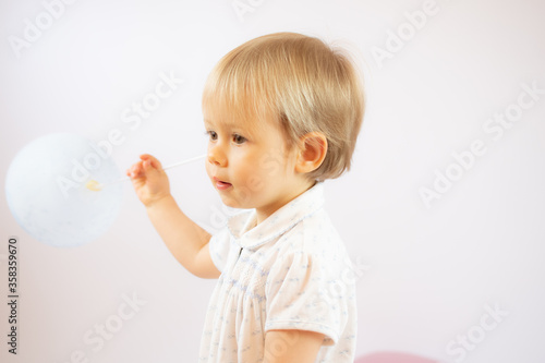 Blond baby playing with a balloon