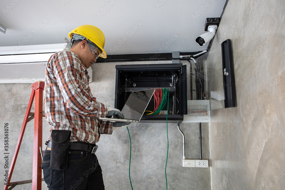 Young network administrator pluging in wires. Electrician engineer tests electrical installations and wires on relay protection system Young network administrator pluging in wires. Electrician engineer tests electrical installations and wires on relay protection system