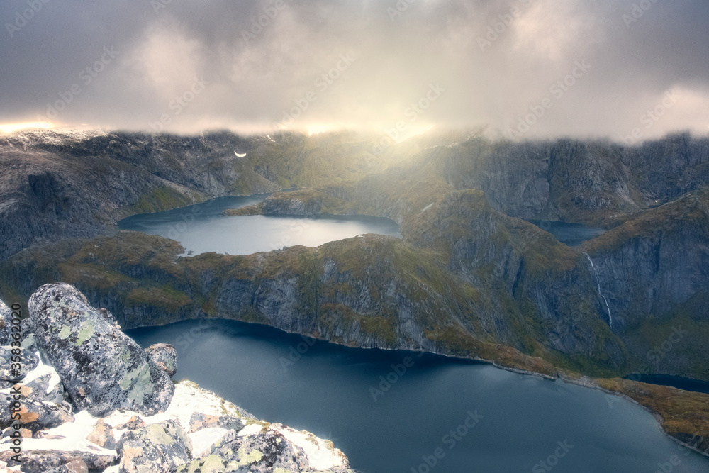 Landscape of harsh Norway, Lofoten Islands. Storm clouds and sunlight over lakes and mountains. Trekking to Munkan Mountain