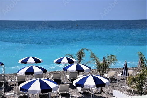 Ombrelloni bianchi e blu in spiaggia di fronte al mare azzurro