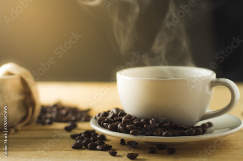 Roasted coffee beans with a smoke cup on a wooden table, dark background.
