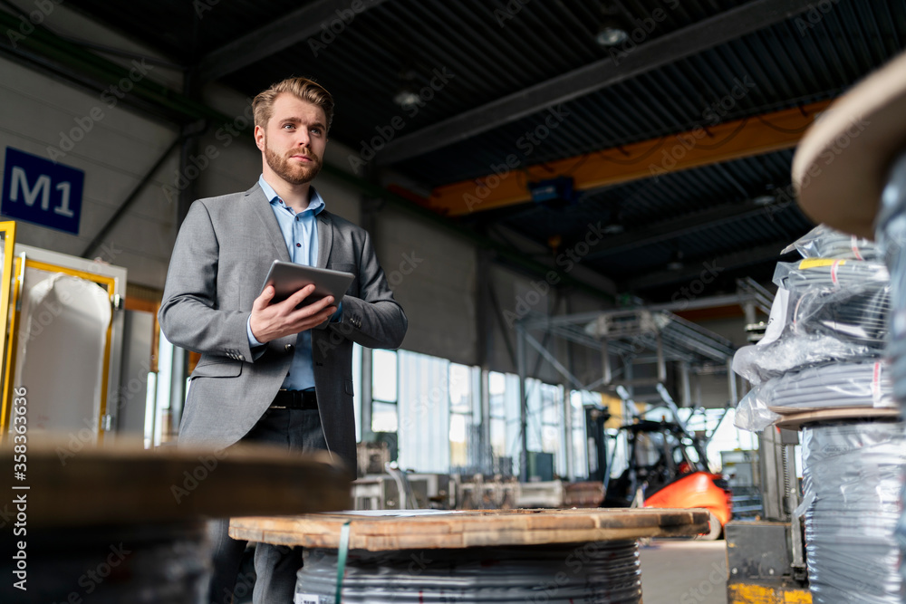 Young businessman with tablet in a factory Young businessman with tablet in a factory