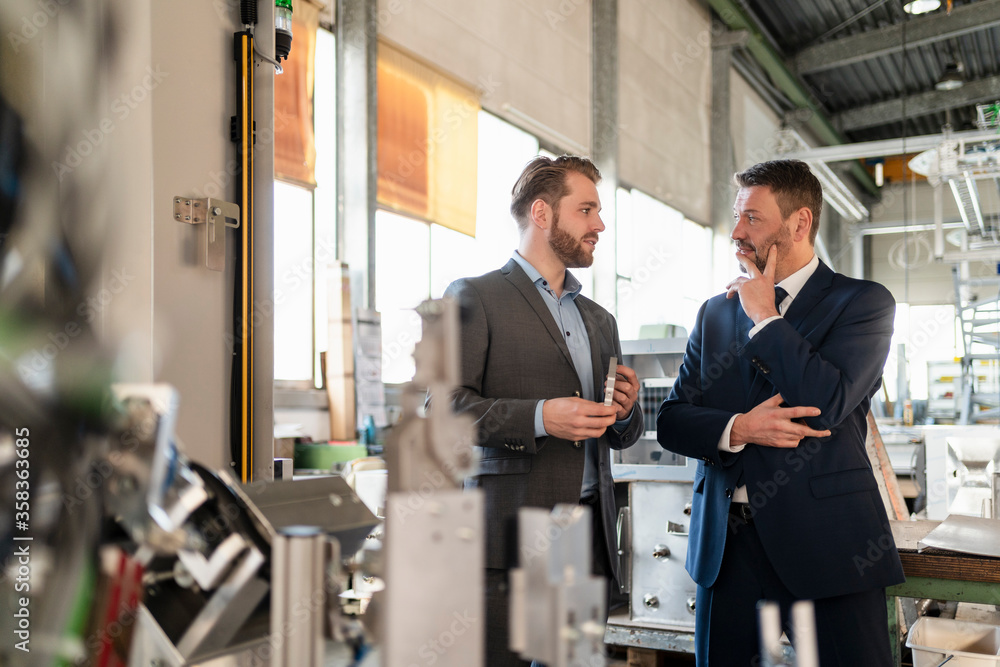 Two businessmen having a meeting in a factory Two businessmen having a meeting in a factory