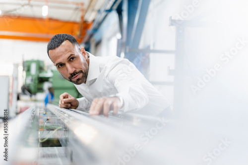 Businessman examining metal rod in factory hall