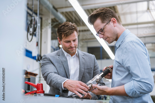 Two businessmen examining a product in a factory photo