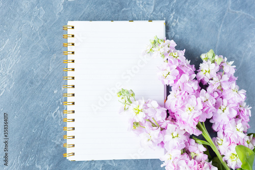 Desk top view, blank notebook with Purple flowers top view, flat lay. Mock up. Copy space. Space for text. 