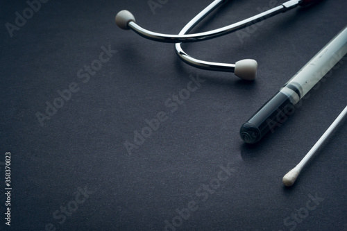 Medical swab and stethoscope closeup on black background. Health care and copy space concept