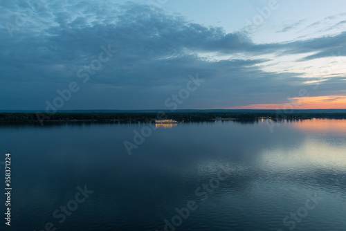 Panorama a white three deck ship lit by lights on the morning river