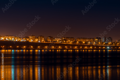Cityscape of town Galati on Danube river from shore of Braila County, Romania at sunset