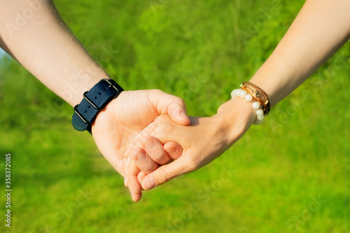 Man and woman hold hands on a background of green trees. In the frame only hands close-up. The concept of love, romance, relationship, being together, walking. © Ольга Холявина
